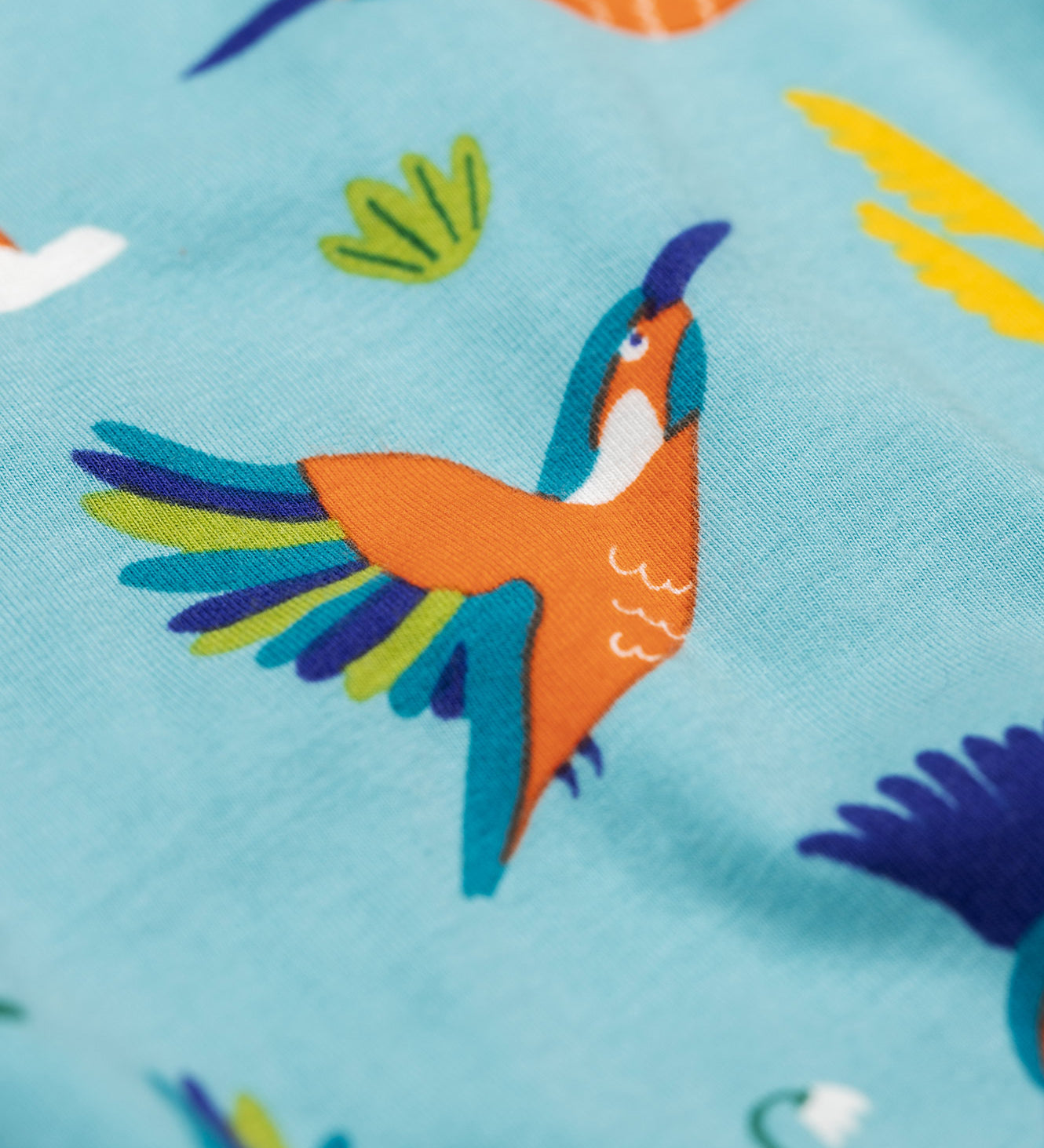 A close up of the kingfisher on the Frugi sofia skater dress in kingfisher skies available at Babipur. A GOTS organic cotton skater dress in light blue with a lovely playful kingfisher print.