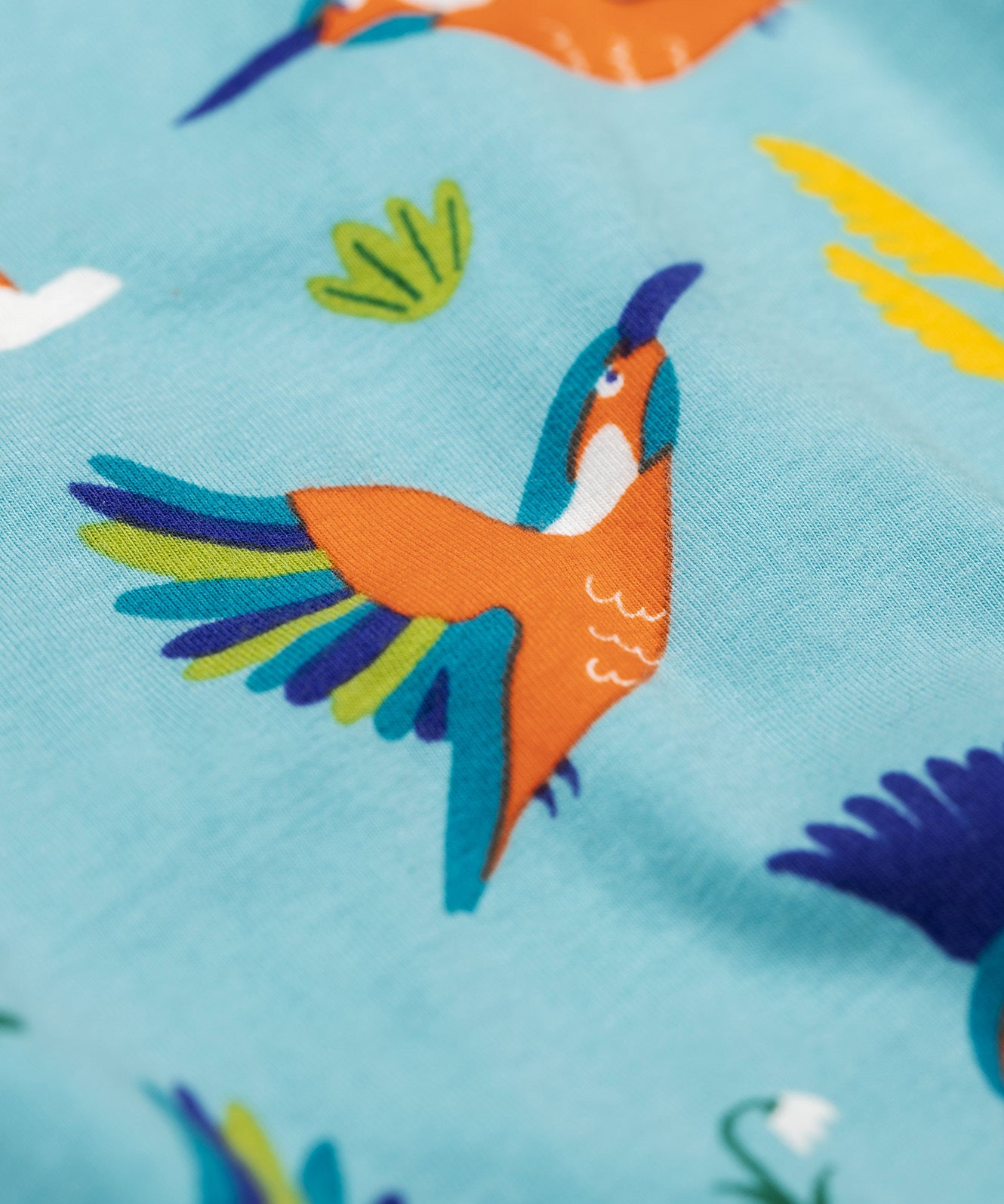 A close up of the kingfisher on the Frugi sofia skater dress in kingfisher skies available at Babipur. A GOTS organic cotton skater dress in light blue with a lovely playful kingfisher print.