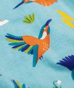 A close up of the kingfisher on the Frugi sofia skater dress in kingfisher skies available at Babipur. A GOTS organic cotton skater dress in light blue with a lovely playful kingfisher print.