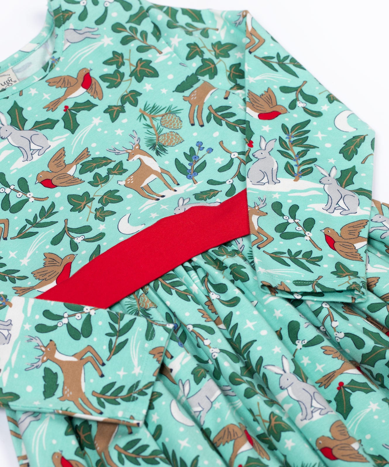 A close up of the front of the Frugi party skater dress in festive forest available at Babipur. A GOTS organic cotton dress in mint green with a playful winter / festive print. Features a red tie around the waist