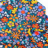 A close up of the Frugi sofia skater dress in navy / retro flowers available at Babipur. A GOTS organic cotton skater dress in navy with a bright retro floral design.