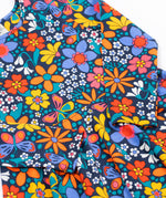 A close up of the Frugi sofia skater dress in navy / retro flowers available at Babipur. A GOTS organic cotton skater dress in navy with a bright retro floral design.