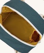 Fluf zip lunch bag in a teal blue colour opened with a mustard yellow inner lining with a white handle and zip detail on a cream background.