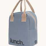 Fluf zip lunch bag in a light blue colour with a light brown handle and lunch logo on the bottom with a white zip side details on a cream background