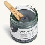 A opened jar of the activated fluoride Georganics toothpaste with the wooden spatula dipped in the jar