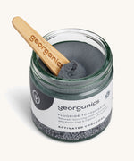 A opened jar of the activated fluoride Georganics toothpaste with the wooden spatula dipped in the jar