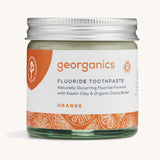 a jar of the Georganics orange fluoride toothpaste on a cream background