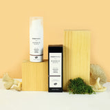 The Green People Nordic Roots Truffle Night Cream and its box is on a yellow background with the cream tube on a wooden block, with moss and mushrooms surrounding