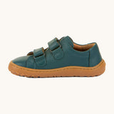 A side image of the Froddo barefoot base children's shoe in petroleum available at Babipur. A dark turquoise natural leather low profile shoe showing the 2 velcro fasteners looped through and the brown grippy sole