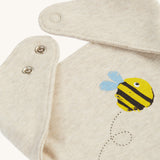A closer look at the bib on the Frugi Baby Gift Set - Buzzy Bee. A dark cream cotton fabric, with a buzzy bee on the front