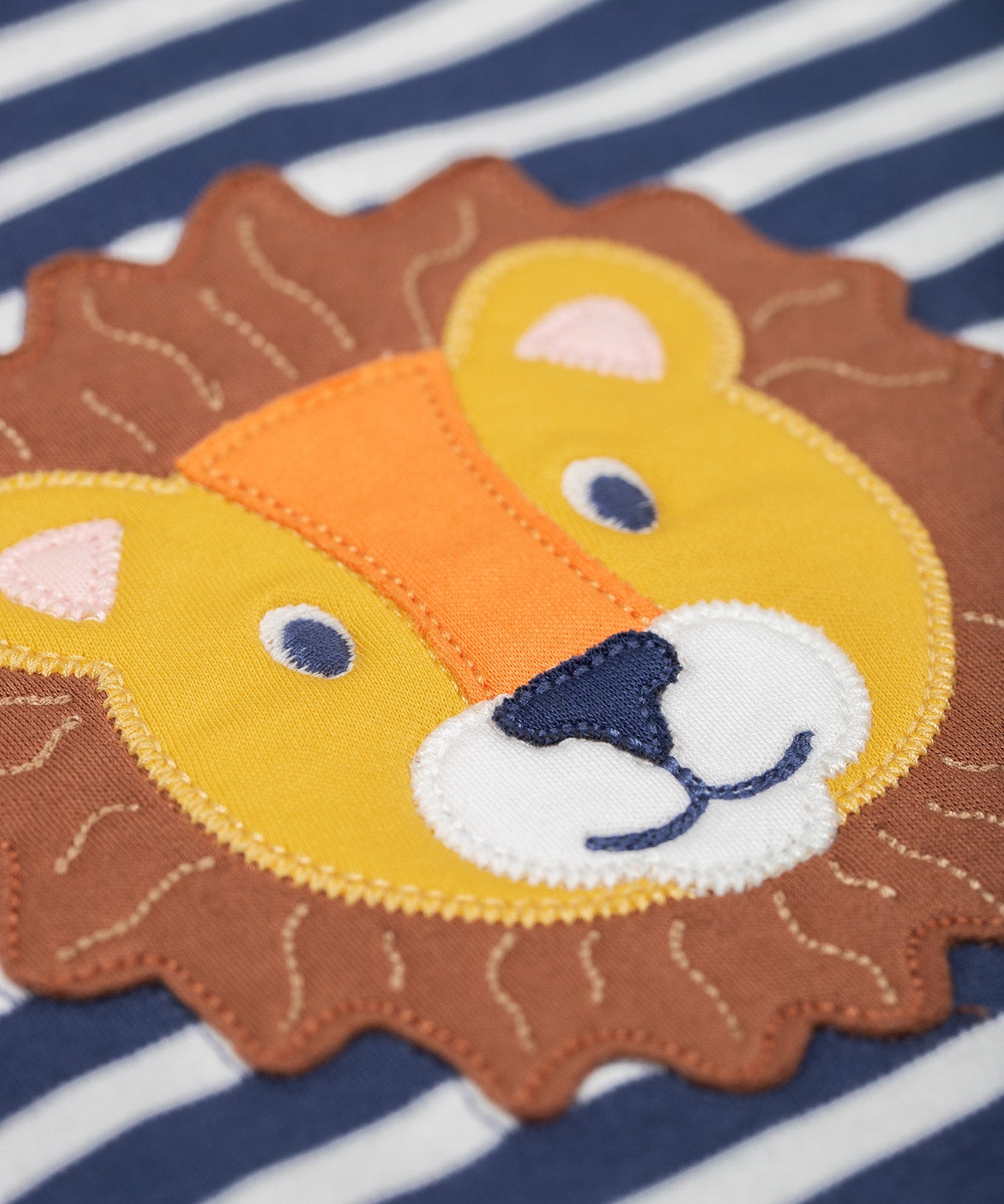 A close up of the lion's head applique on the Frugi discovery applique top in stripe/Lion available at Babipur