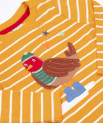 A close up of the robin applique on the Frugi discovery applique top in stripe/polar bear available at Babipur. Robin is wearing a greeb winter hat, top and blue boots.