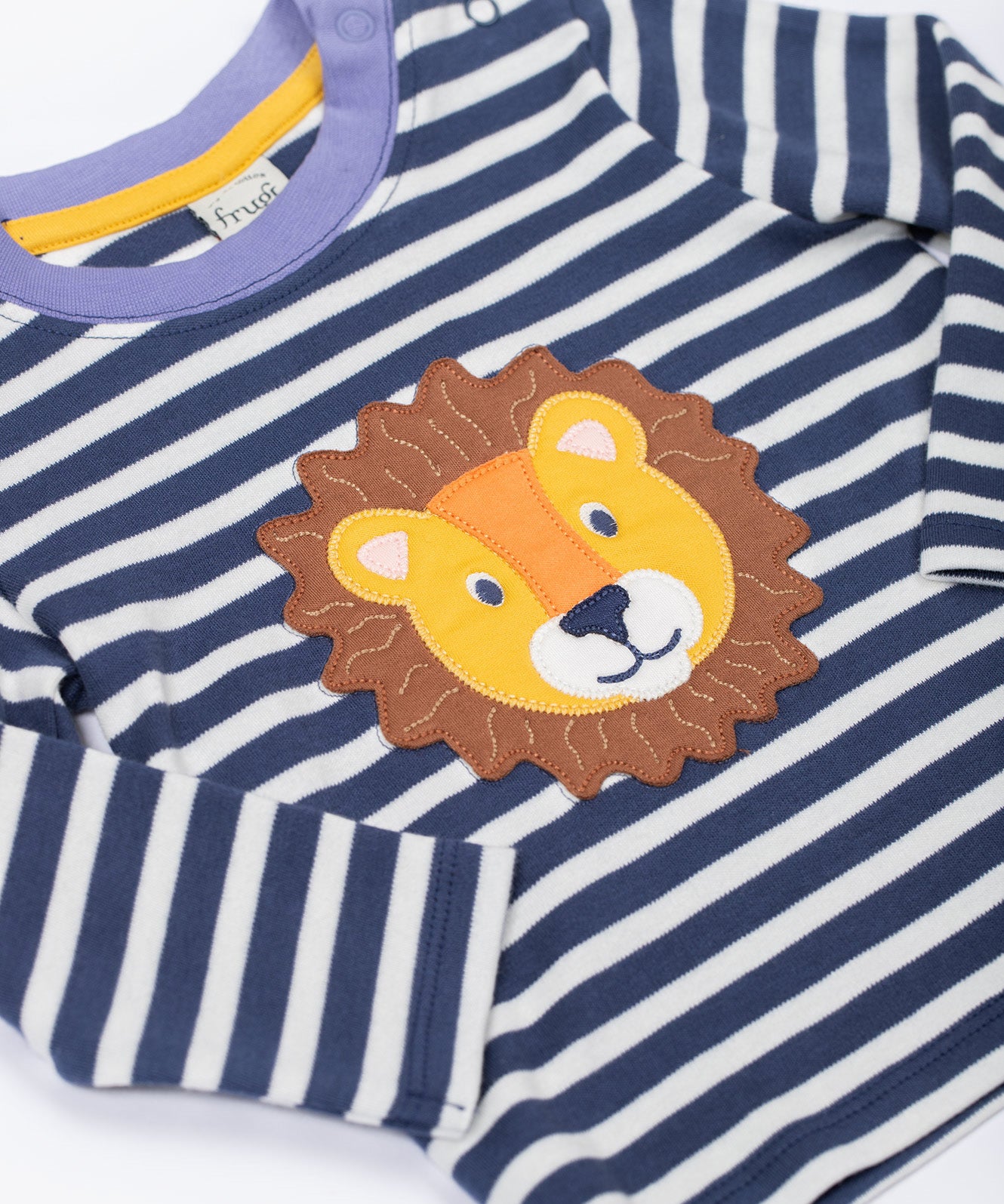 A close up of the Frugi discovery applique top in stripe/Lion available at Babipur showing the applique detail and light blue trim on the neck