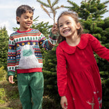 2 children playing in the woods. A boy is wearing the the Frugi forest fairisle/yeti jumper and the girl is wearing the red robin reindeer cord dress.  Both are GOTS organic cotton garments and available at Babipur.