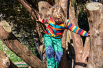 A child Playing in the trees and wearing the Frugi Autumn stripe ted fleece available at Babipur.. A long sleeve striped thick fleece with light blue trim and turn up collar.