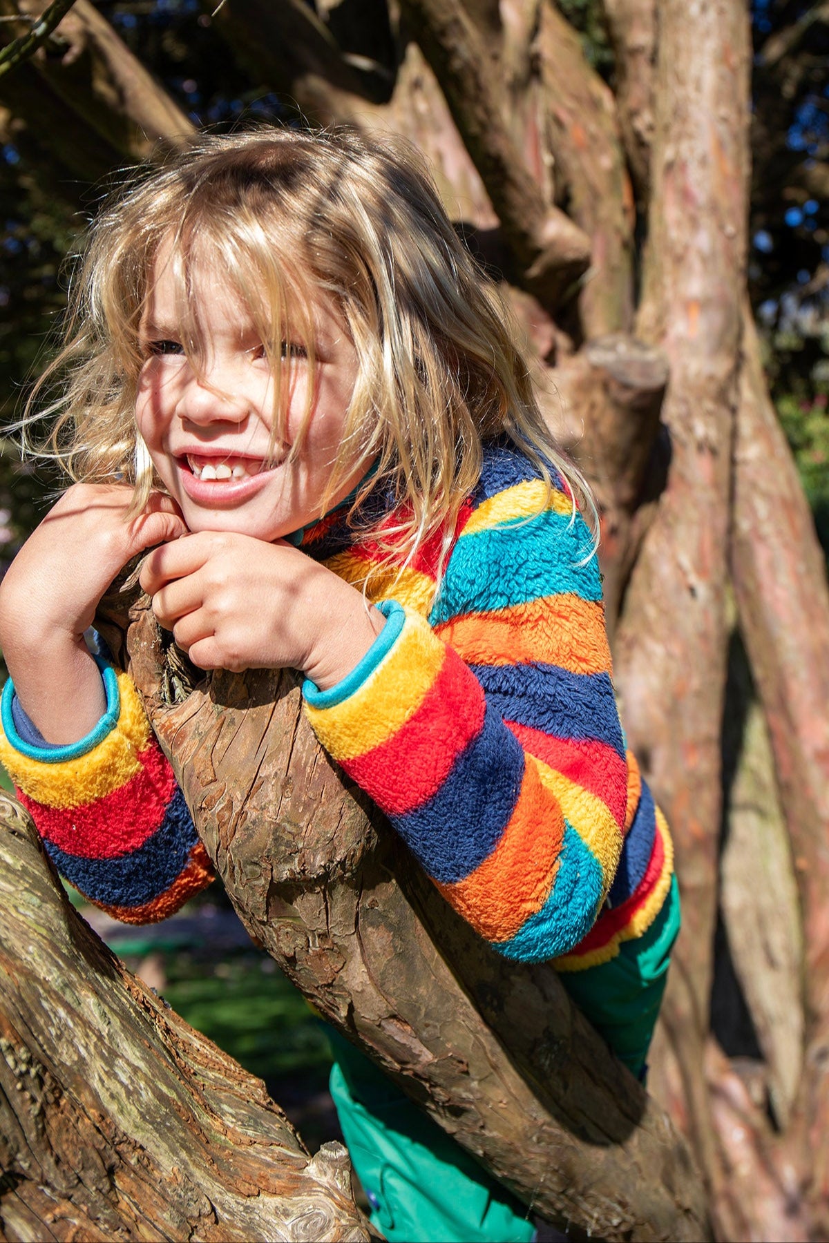 A close up of a child wearing the Frugi Autumn stripe ted fleece available at Babipur. Showing the fleece and light blue trim detail