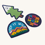 A close up of the Frugi kids keep it wild patches showing the different designs. Features a playful tree patch, a keep it wild slogan patch and lets have fun slogan patch.