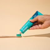 A hand squeezing the Georganics fluoride free toothpaste with pre and prebiotcs in fresh mint flavour available at Babipur on a Georganics tothbrush