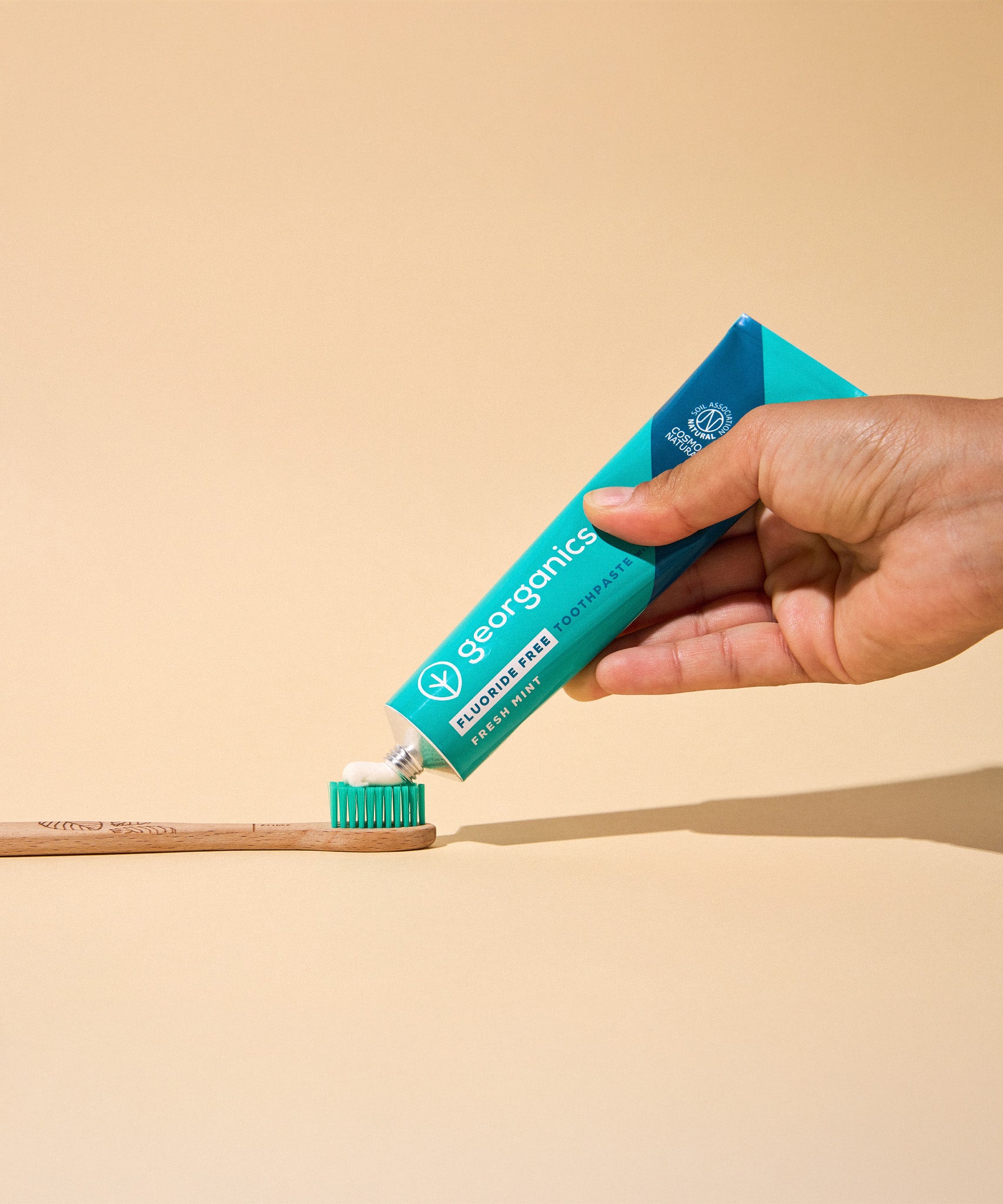 A hand squeezing the Georganics fluoride free toothpaste with pre and prebiotcs in fresh mint flavour available at Babipur on a Georganics tothbrush