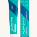 Georganics fluoride free toothpaste with pre and prebiotcs in fresh mint flavour available at Babipur standing next to the matching turquoise cardboard packaging.