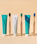 A group of Georganics toothpastes available at Babipur standing next to Georganics bamboo toothbrushes
