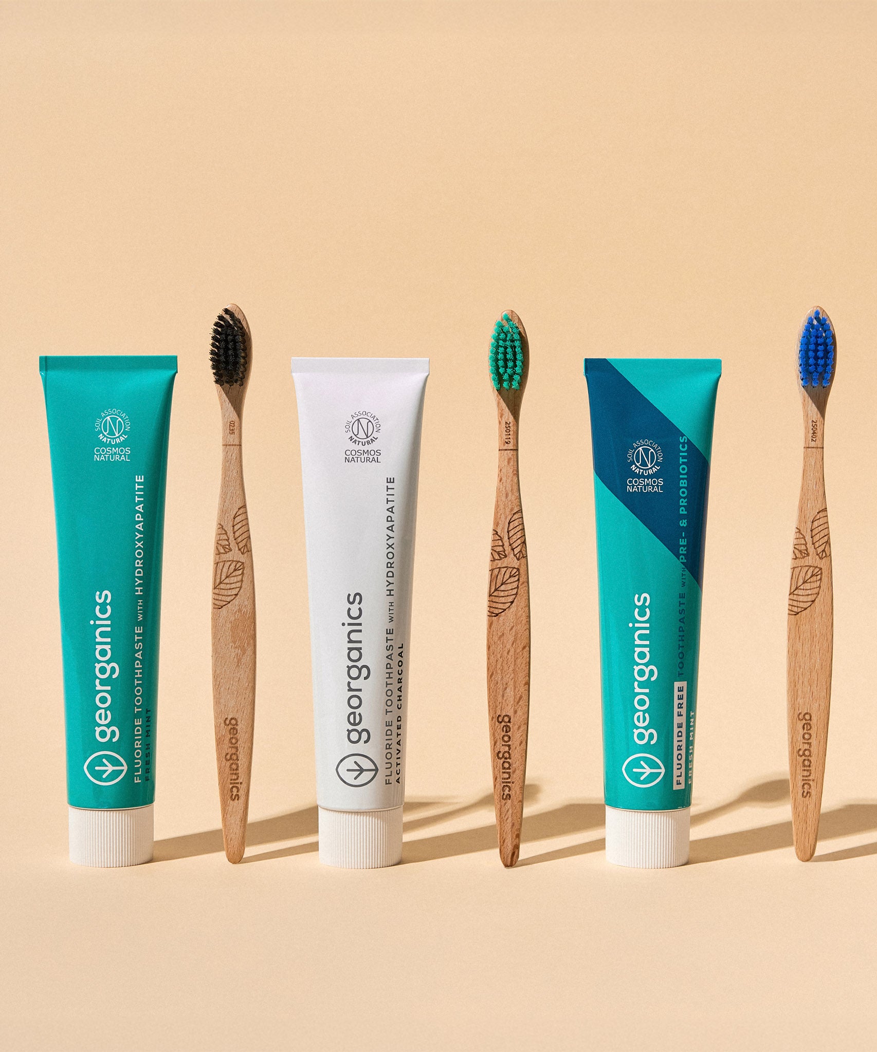 A group of Georganics toothpastes available at Babipur standing next to Georganics bamboo toothbrushes