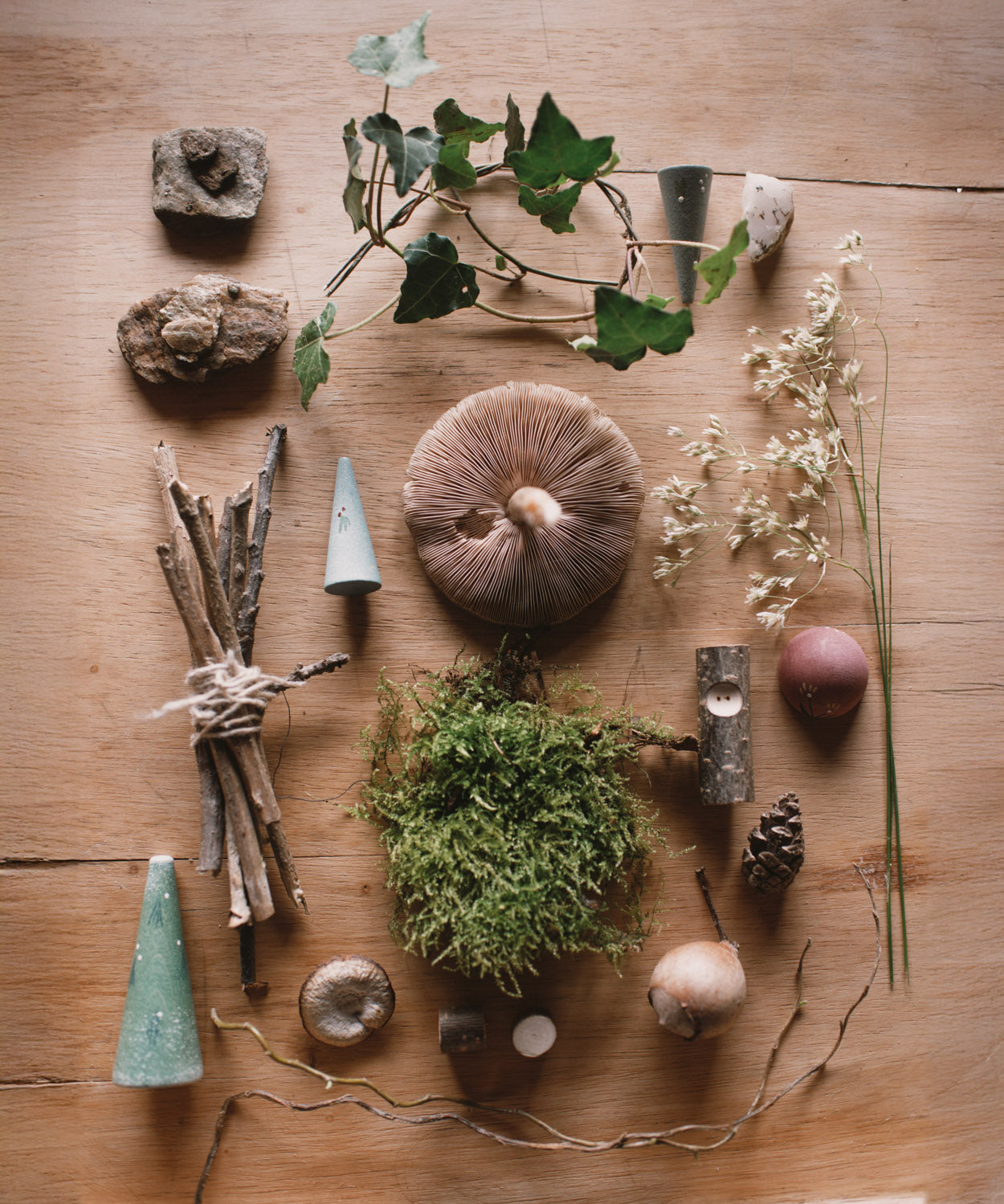 A flatlay image using the different piece from the Grapat advent calendar available at Babipur and various woodland leaves, miss and mushrooms.