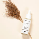The Green People Nordic Roots Hyaluronic Booster Serum on a light peach background with dried grass underneath