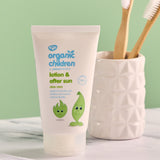 Green People organic children's aloe vera lotion & aftersun in 50ml bottle standing on a stone surface next to a toothbrush holder