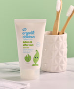 Green People organic children's aloe vera lotion & aftersun in 50ml bottle standing on a stone surface next to a toothbrush holder