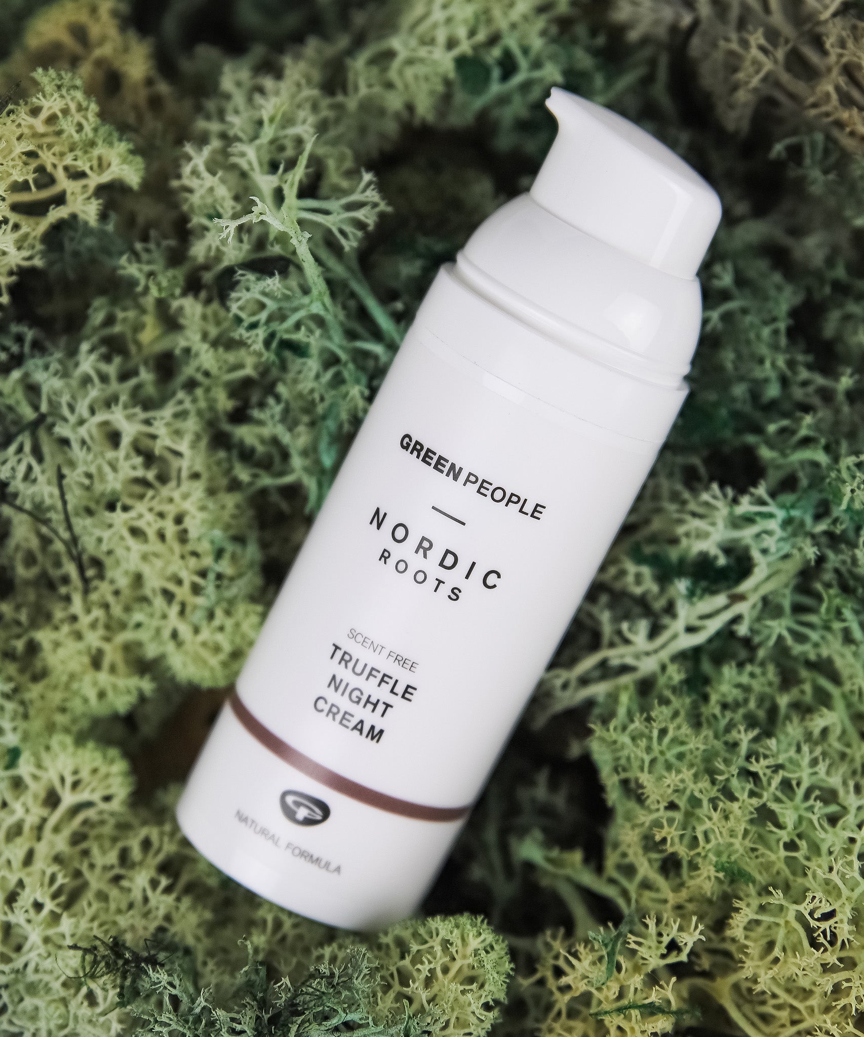 The Green People Nordic Roots Truffle Night Cream - 50ml is laid on a mossy green background