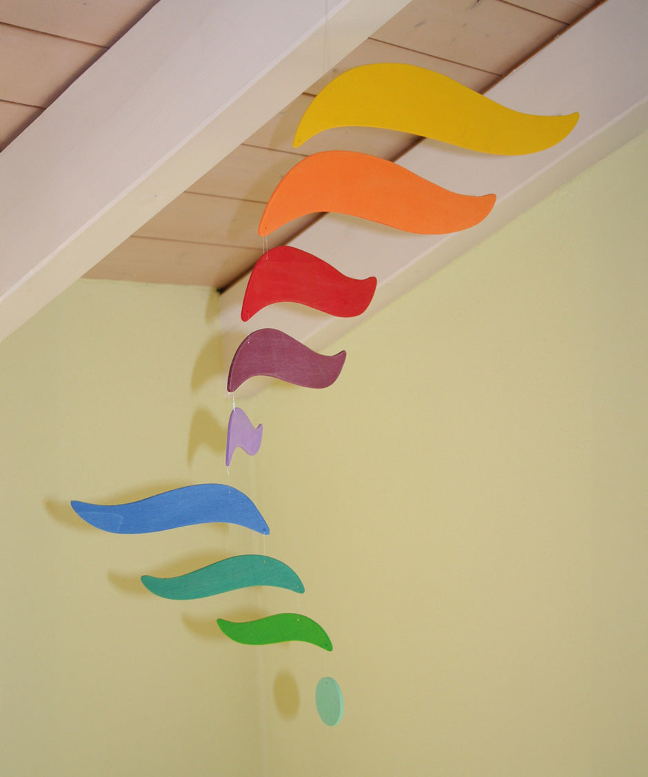A close up of the Grimms wooden harmony mobile available at Babipur. Showing the different coloured wings in motion and hanging under a ceiling