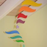 A close up of the Grimms wooden harmony mobile available at Babipur. Showing the different coloured wings in motion and hanging under a ceiling