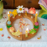 A beautiful Grimm's Celebration Ring with cream coloured Grimm's candles in candle holders, along with pretty Grimm's decorative figures make up a wonderful Sprint time display
