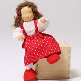 Grimm's Brown Haired Girl Doll - Lana is sat on a wooden block, showing the flexible arms and legs of the fabric doll