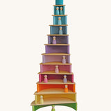 The Grimm's 12 Pastel Friends stood inside different levels of a Grimm's "cake" made from a Grimm's Pastel Rainbow and Natural Semi Circles