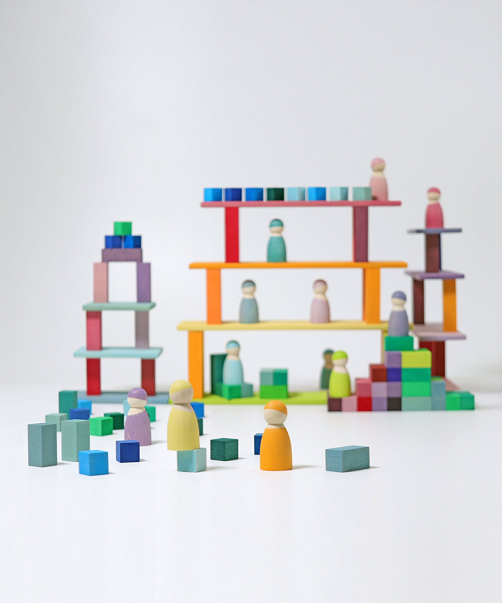 The Grimm's 12 Pastel Friends stood on various levels of a built Grimm's wooden block building