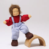 The Grimms Doll Peter has its foot on a piece of Grimm's natural rainbow, to show the flexibility of the dolls legs