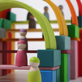 The Grimm's 12 Pastel Friends stood on a Grimm's building set up of colourful blocks and rainbow arches
