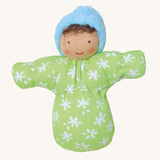 Baby Leo has brown hair and light brown skin, and is wearing a green gown with white flowers and a blue cap. The image is on a cream background