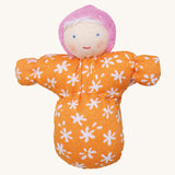 Grimm's Baby Mia Doll has a lovely warm smiling face. Mia also has a handmade fabric orange and white flower body, a light pink hat and white hair. The image is on a cream background