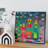 A colourful puzzle piece art work, on the Grimm's Small magnetic blackboard. In front of the board is a Grimm's monochrome house and a white vase with dried flowers in it