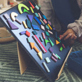 A child playing with the Grimm's Magnetic Blackboard, and has created a pattern using the Grimms magnetic puzzle pieces