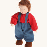 Grimm's Brown Haired Boy Doll - Peter. Peter has brown hair and is wearing a red top with blue trousers and braces, on a cream background