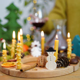 A Grimm's Wooden Celebration Ring, filled with Grimm's wooden Christmas decorative figures and candles in brass holders. There are also other decorative items such as a walnut, cinnamon stick, pine cone and conkers to create an uplifting winter display