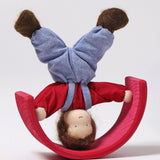 Grimm's Brown Haired Doll - Peter is doing a handstand on a red piece of a Grimm's wooden rainbow. Peter is upside down and the rainbow piece is resting on the top of its arch like a sea-saw