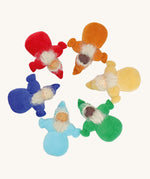 Grimm's Rainbow Dwarfs, placed in a circle. Each doll is one colour of the rainbow and is light blue, dark blue/indigo, red, orange, yellow or green. Each doll has a warm smiling face a long beard and a pointed hat. The image is on a cream background