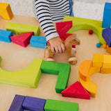 A child is pushing a wooden Grimm's horse through a maze they have created using the Grimm's Basic Building Set