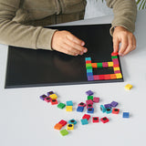 A child creating a puzzle with small magnetic blocks, using the Grimm's Small Magnetic Blackboard