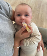 A parent is using the Haakaa Silicone Colostrum Collector with their child, laying in the parents arms